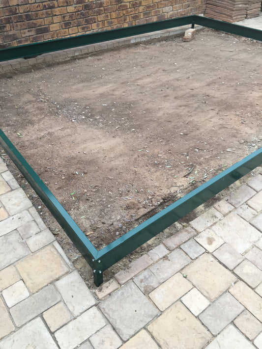 Green aluminium greenhouse base frame installed on soil and brick patio