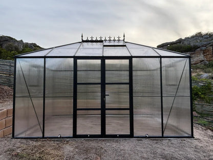 Large glass greenhouse with metal frame in a natural setting