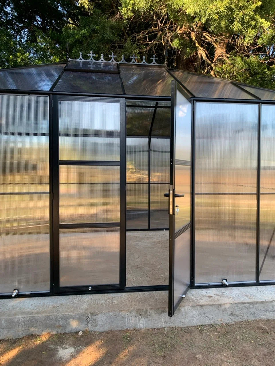 polycarbonate greenhouse with open door in a natural setting
