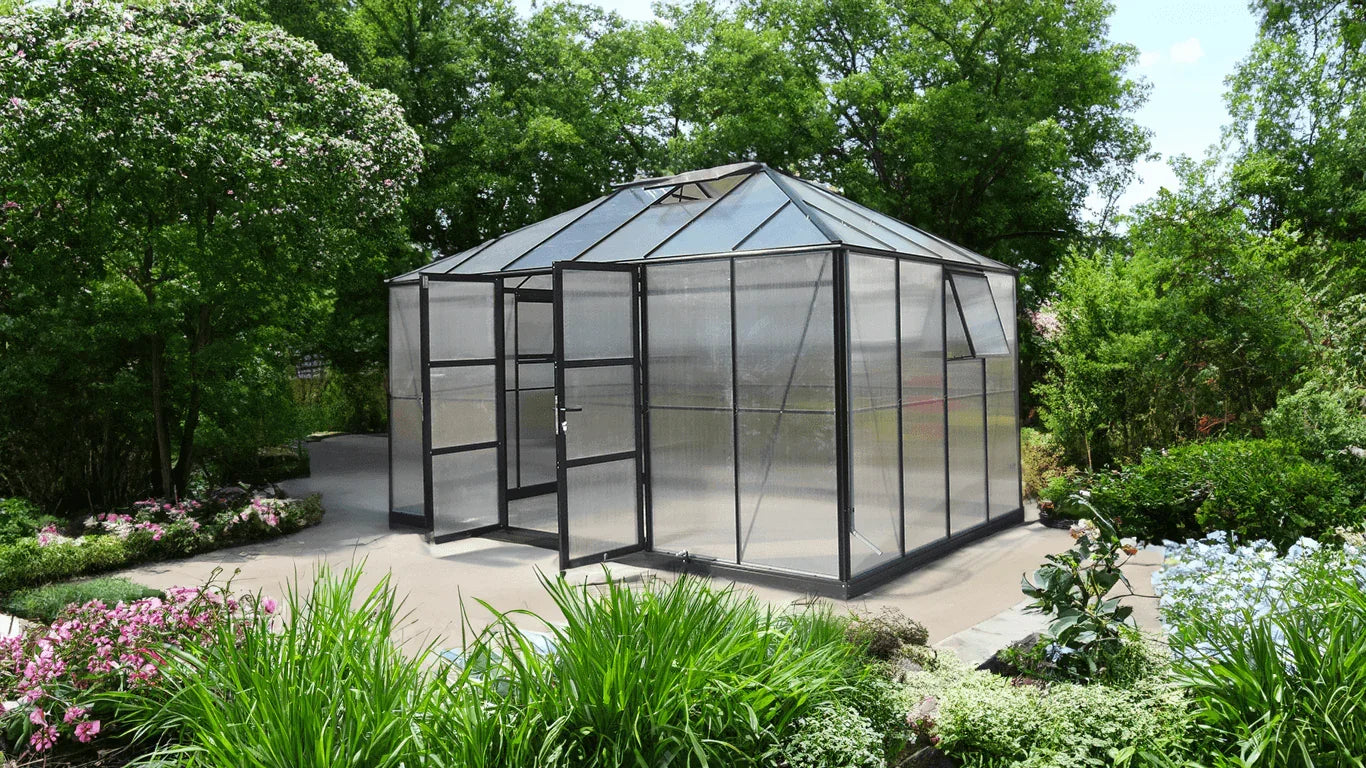 Greenhouse in a garden setting with trees and flowers