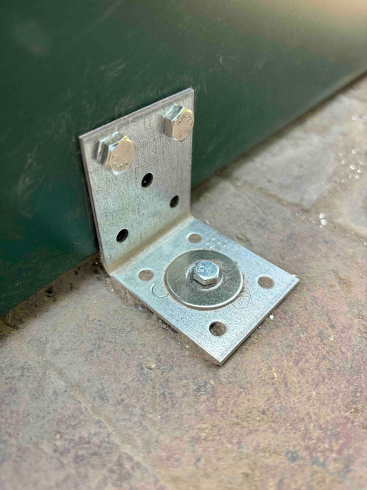 Galvanized steel greenhouse anchor bracket secured with bolts to brick base