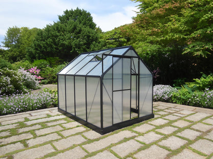Aluminium-frame polycarbonate greenhouse kit on stone patio in a lush garden setting