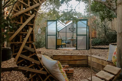 Outdoor garden with greenhouse, and outdoor furniture.