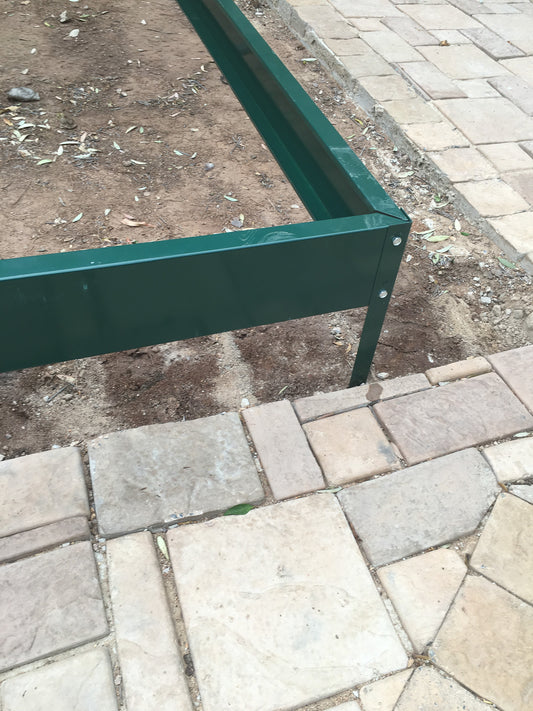 Green metal frame on a paved surface with dirt and grass